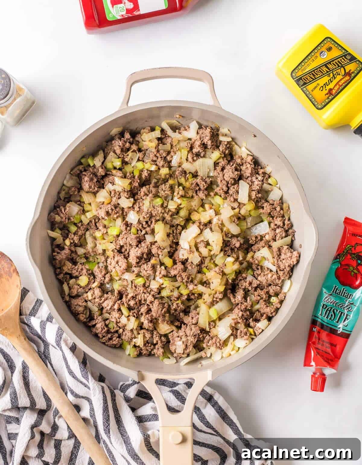 Cooked ground beef in a  skillet with celery and onion.