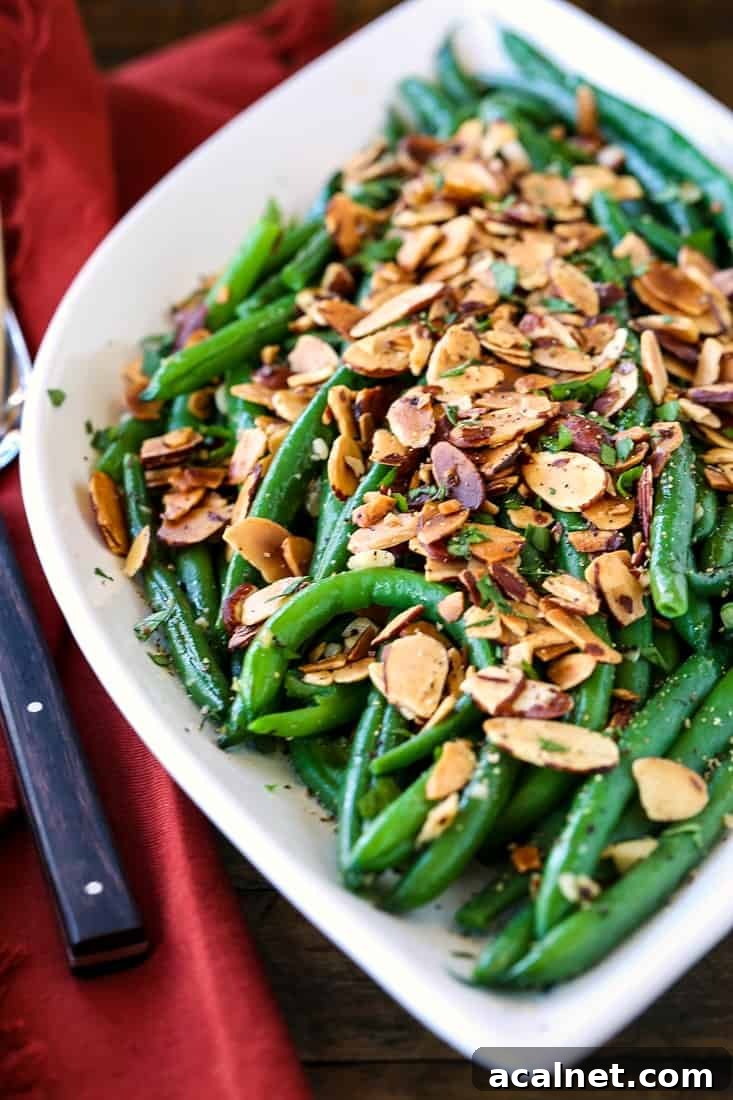 green beans with sliced almonds on a white platter with forks