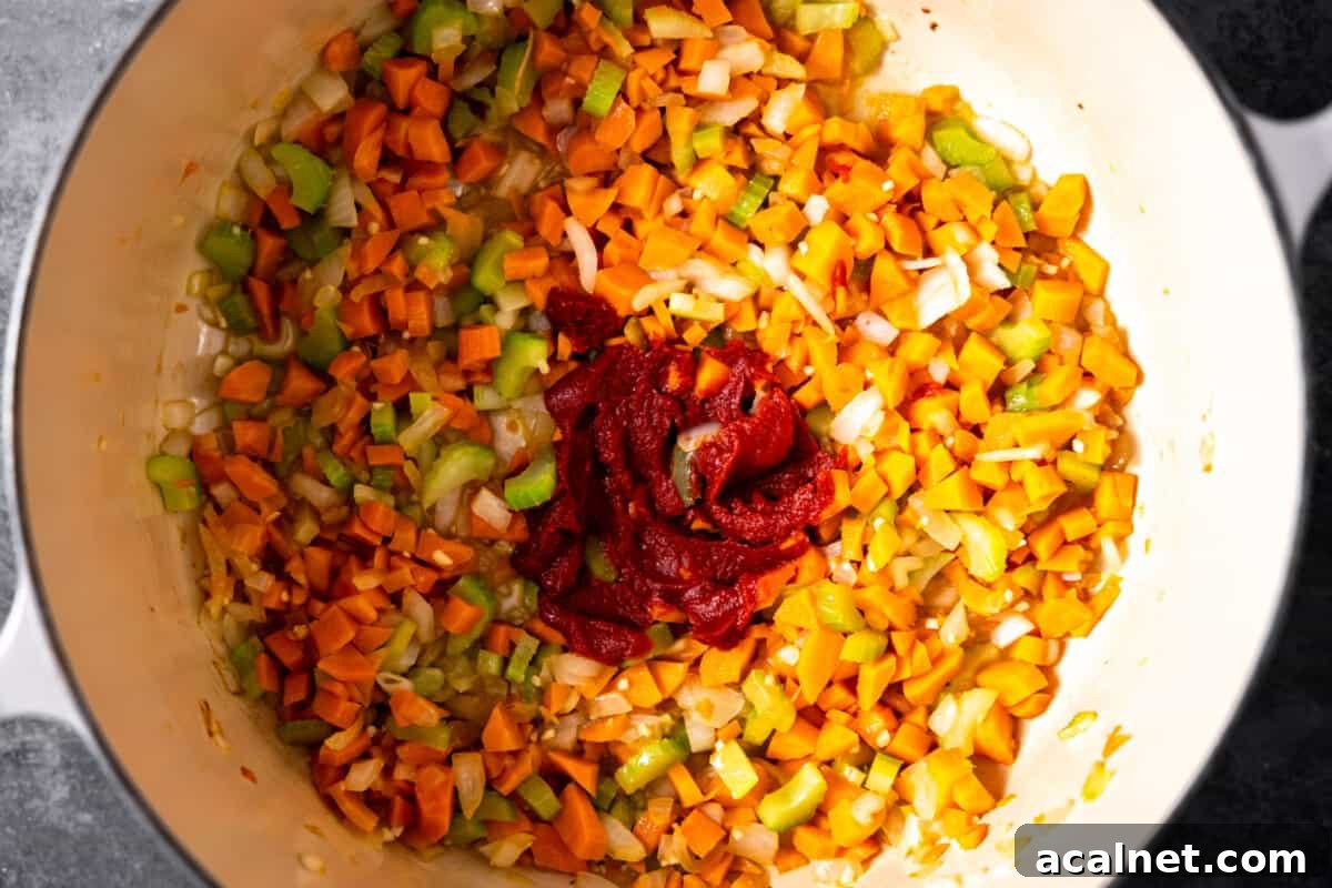 Sauted vegetables in a braising pan with tomato paste added.