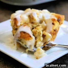 A fork cutting into a gooey cinnamon roll muffin topped with icing on a white plate, reminiscent of homemade monkey bread muffins.