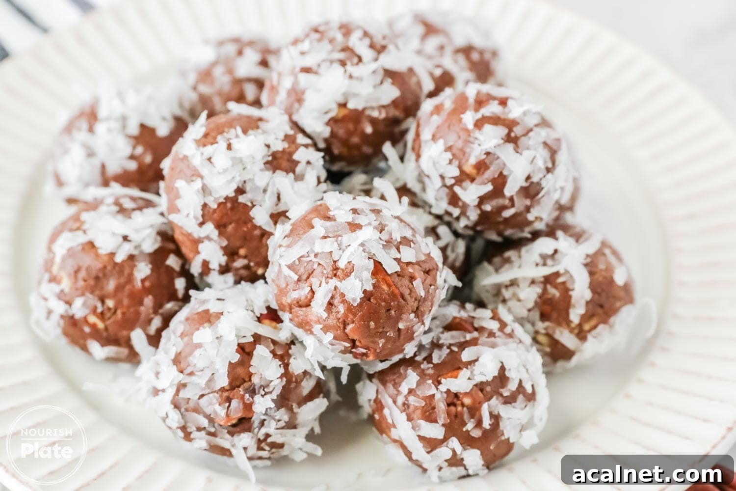 Amaretto Booze Balls: Almond Liqueur Truffles Recipe 2 A plate filled with chocolate Amaretto balls coated in shredded coconut, neatly arranged and ready to serve.