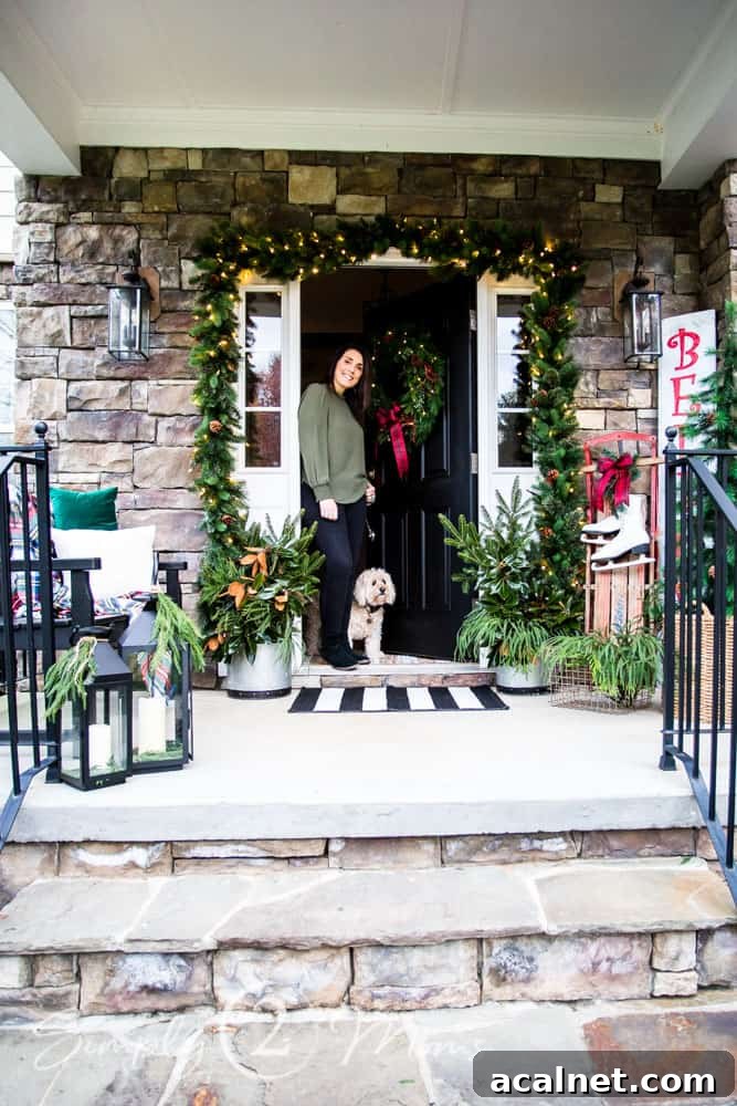 woman and dog standing in door way of front door with porch decorated for christmas