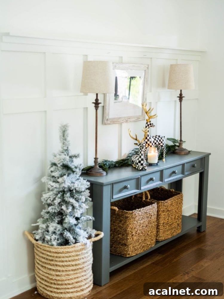 Front entryway with board and batten decorated for Christmas with reindeer on a console table and small flocked tree