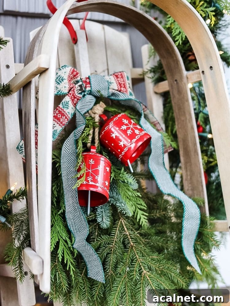 Close up of vintage wood sled decorated for Christmas with greenery, bells, and a bow