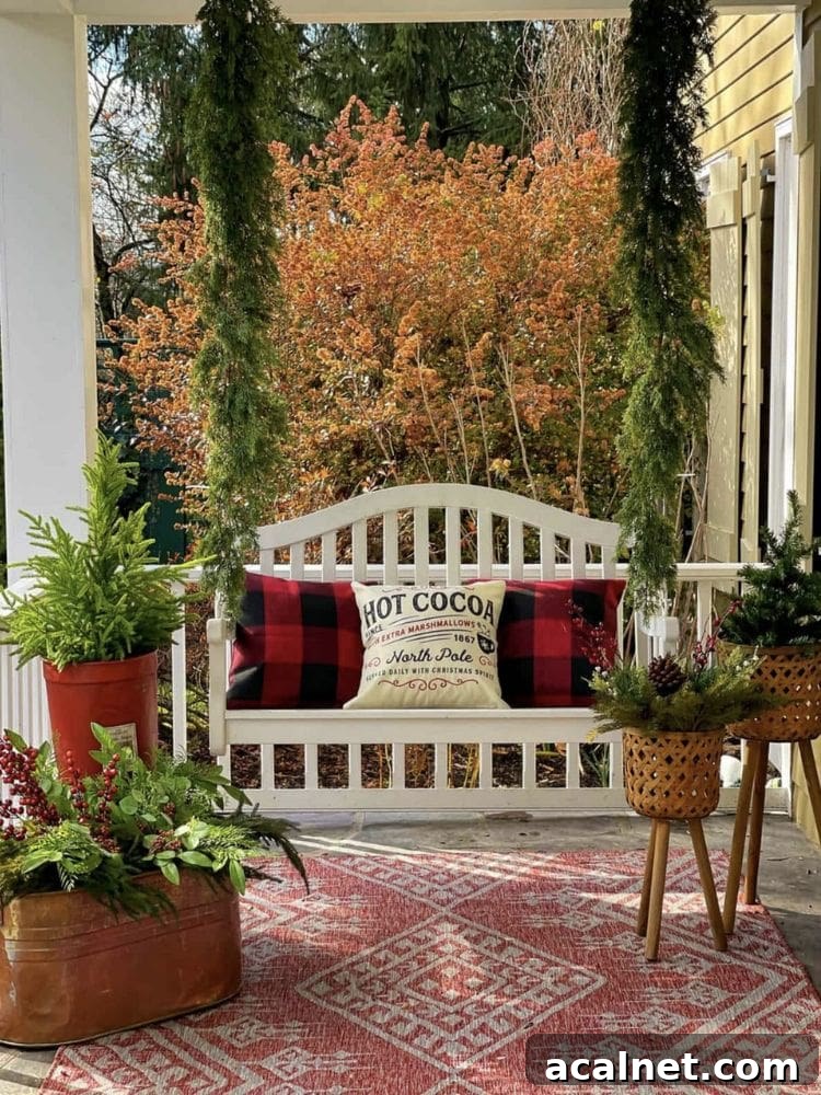 White porch swing with Christmas garland on the chains, buffalo check pillows, and potted evergreens