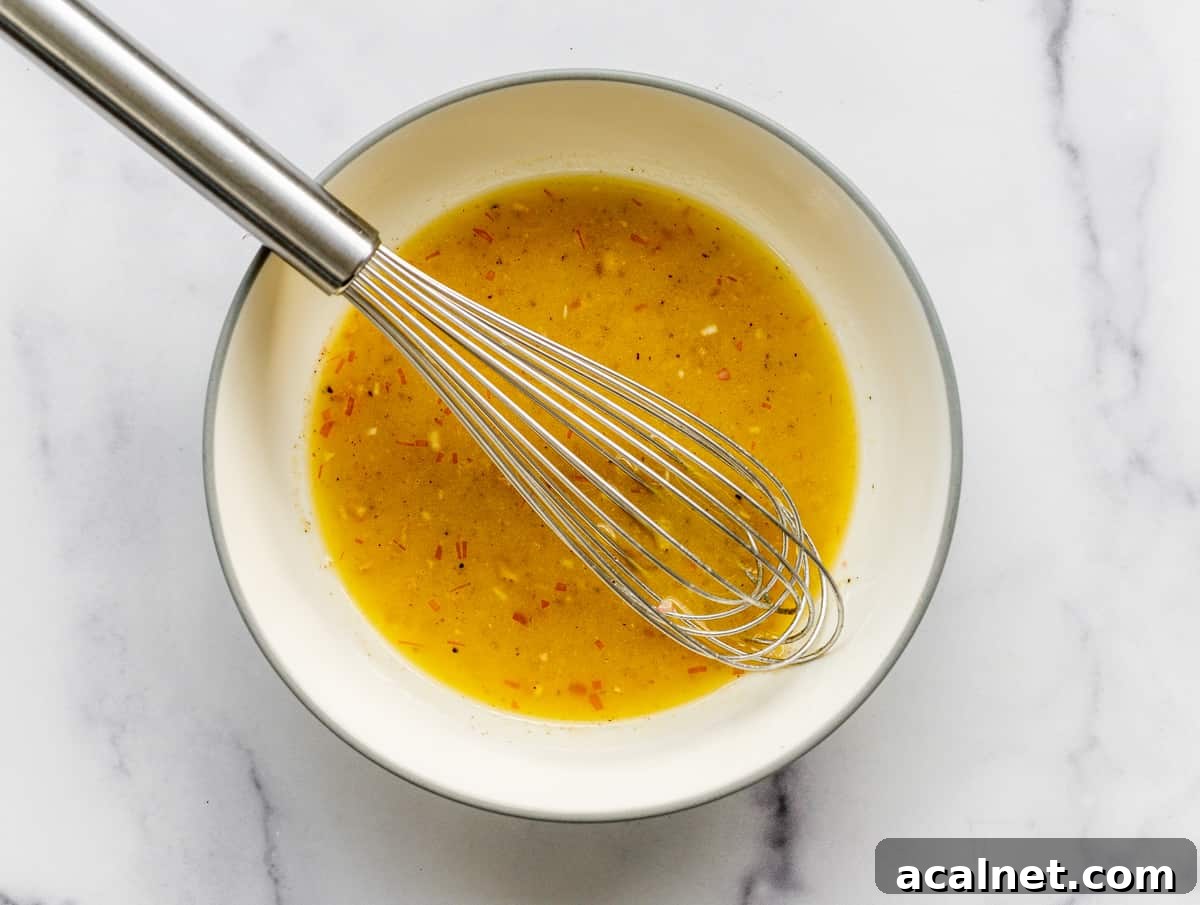 dressing for little gem salad in a white bowl with a whisk.
