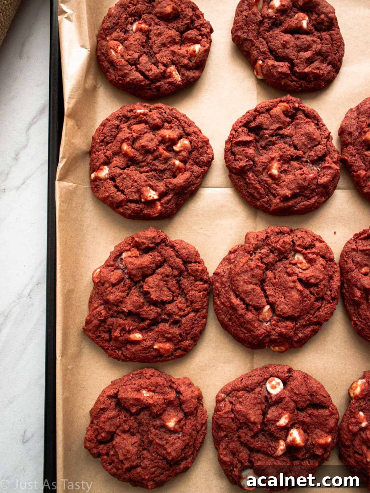 Red velvet chocolate chip cookies on a lined baking sheet.