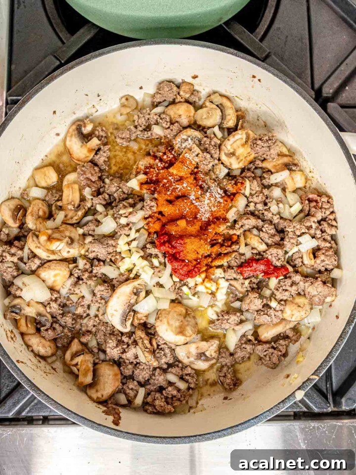 Garlic, tomato paste, paprika, salt, and pepper added to the beef and mushroom mixture.