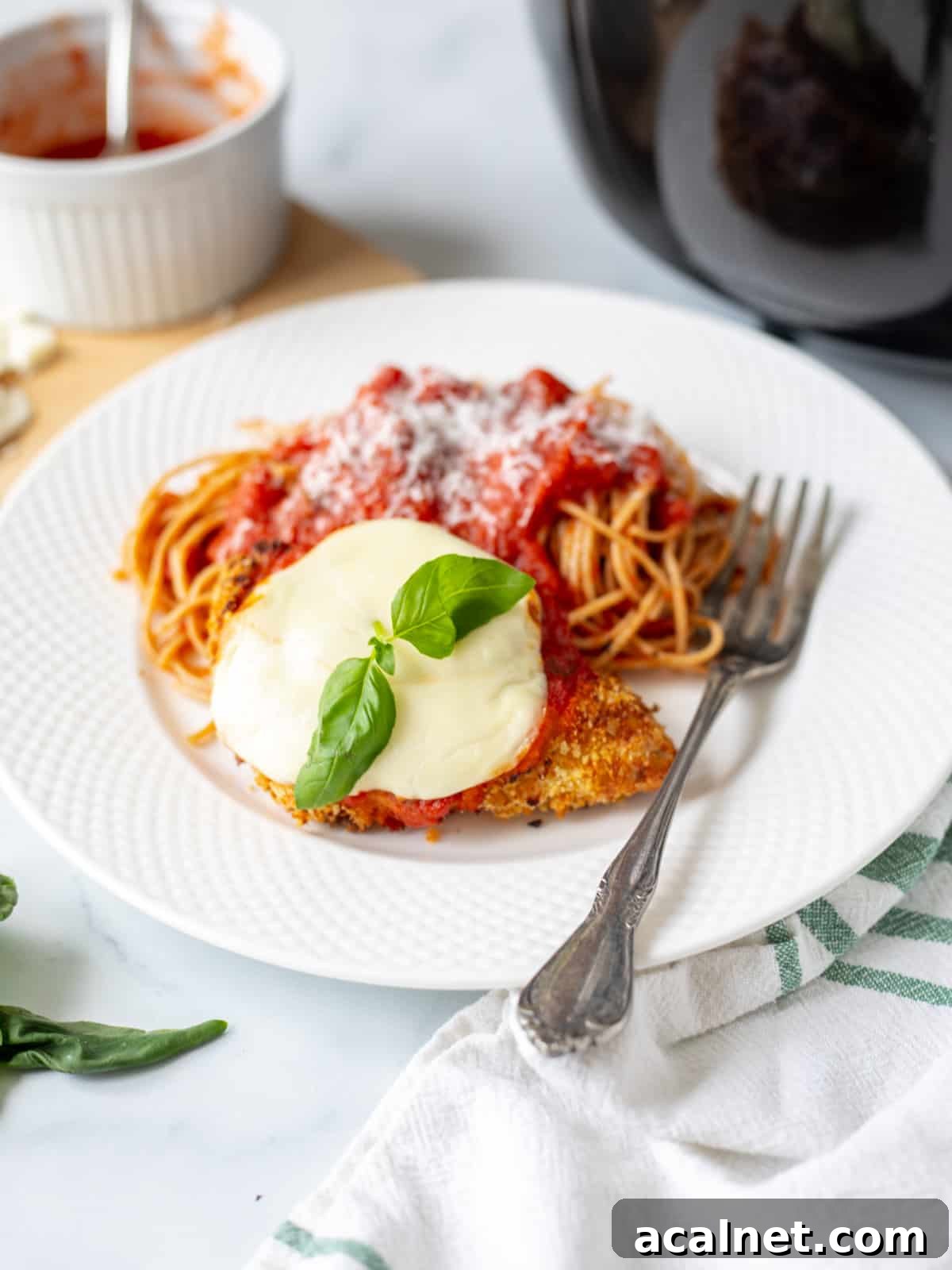 Air Fryer Chicken Parmesan Air Fryer Chicken Parmesan on white plate served with side of spaghetti.
