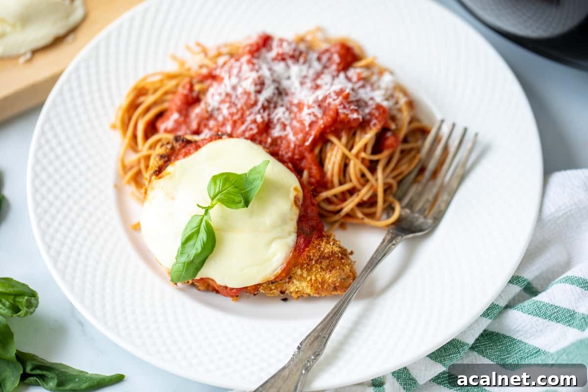 Chicken Parmesan Air Fryer Air Fryer Chicken Parmesan on a plate with a side of spaghetti.
