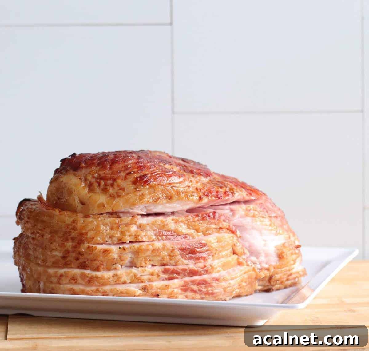 Maple-Glazed Holiday Ham Recipe with Simple Prep and Juicy Results 4 A sliced ham on a white plate.