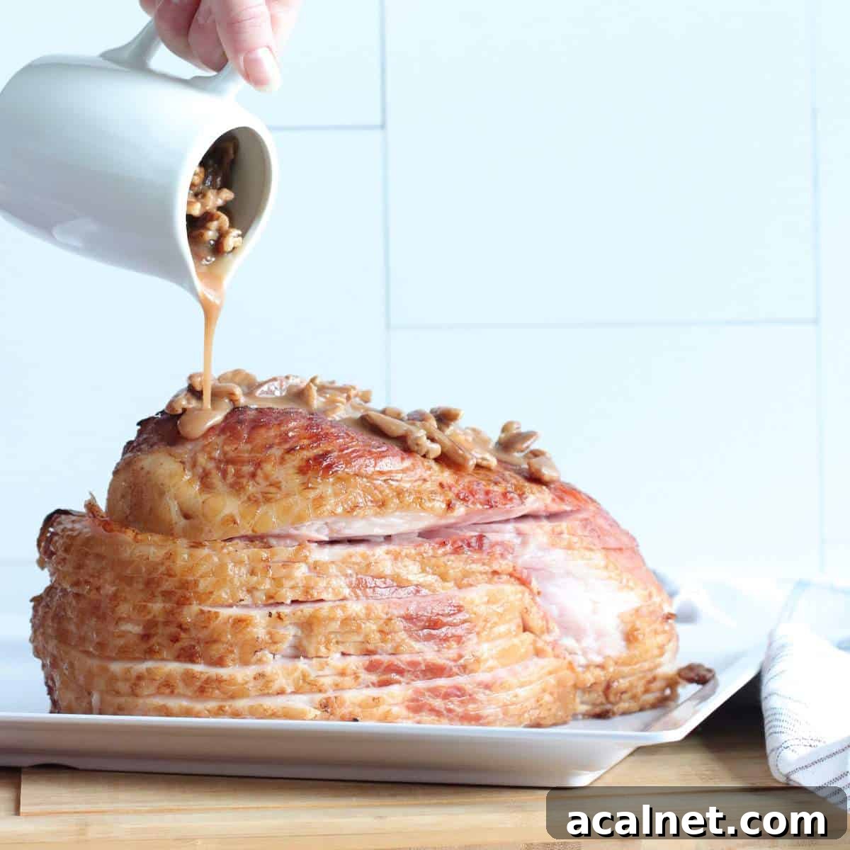 Maple-Glazed Holiday Ham Recipe with Simple Prep and Juicy Results 6 A sliced ham with bourbon pecan glaze being poured over it.