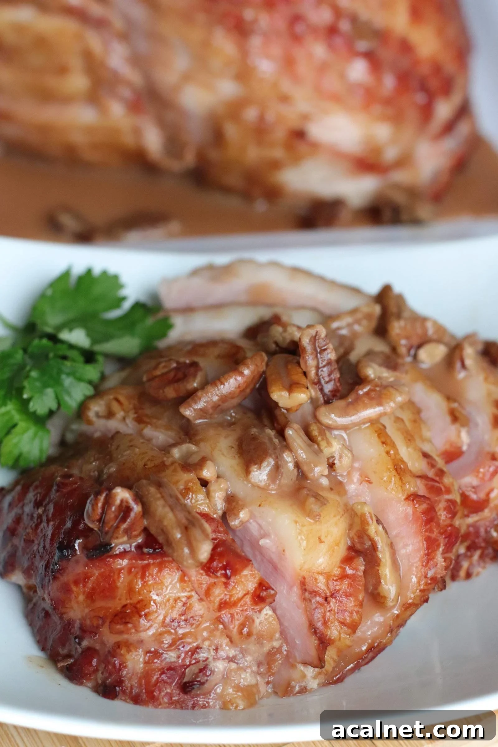 Maple-Glazed Holiday Ham Recipe with Simple Prep and Juicy Results 8 A white plate with bourbon, pecan, and maple glazed ham slices on it.