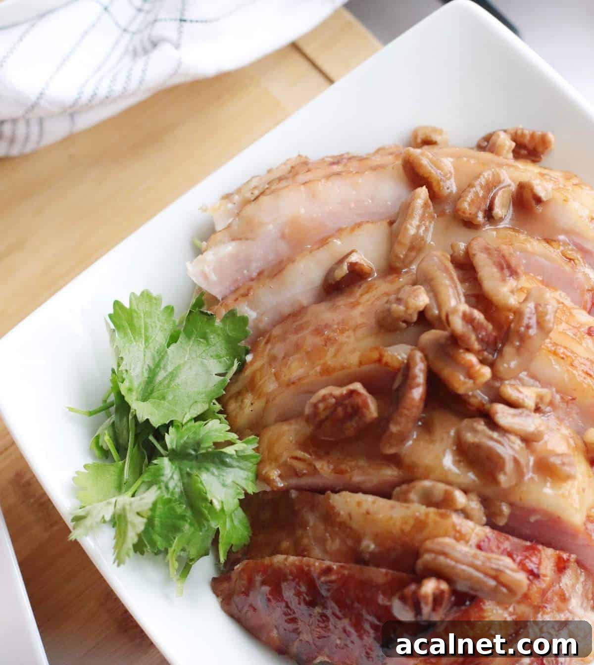 Maple-Glazed Holiday Ham Recipe with Simple Prep and Juicy Results 9 A white plate with bourbon, pecan, and maple glazed ham slices on it.