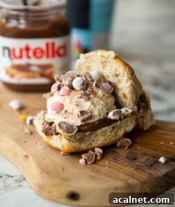 close up shot of hot cross bun ice cream sandwich on small chopping board with ice cream and nutella blurred in background
