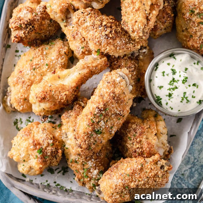 Crispy garlic Parmesan chicken wings on a platter with dipping sauce.