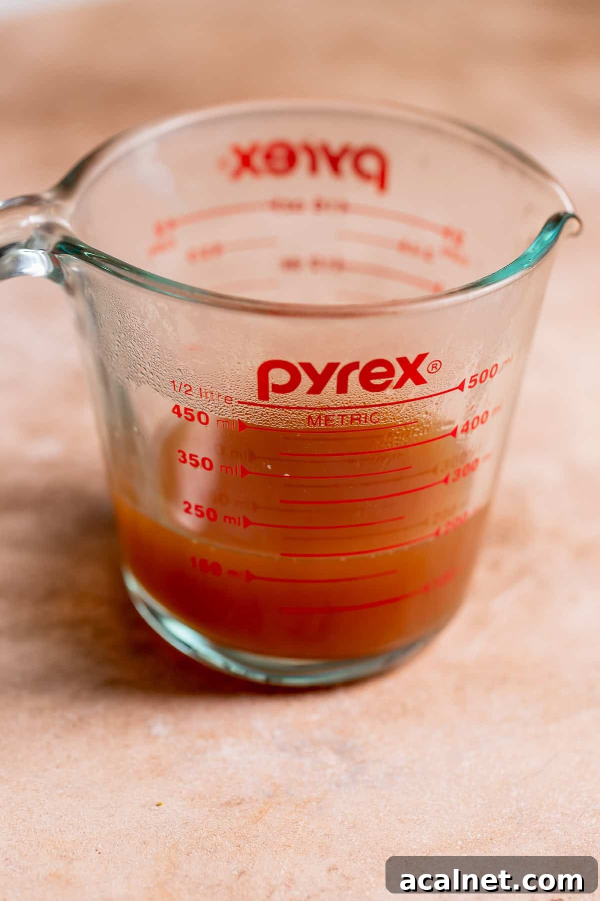 A glass measuring cup with reduced apple cider.