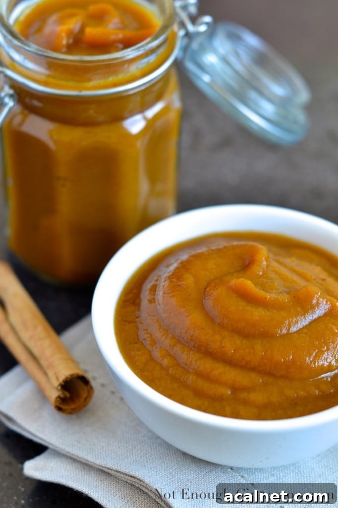 Homemade Slow Cooker Pumpkin Applesauce Recipe 2 Slow Cooker Applesauce with pumpkin and pumpkin spices served in a small white bowl with a cinnamon stick and a jar of slow cooker applesauce in the background