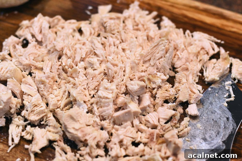 Authentic Chicken Green Chile Tamales Recipe You'll Love 5 24Bite: Shredding boneless chicken breast with an ulu knife on cutting board