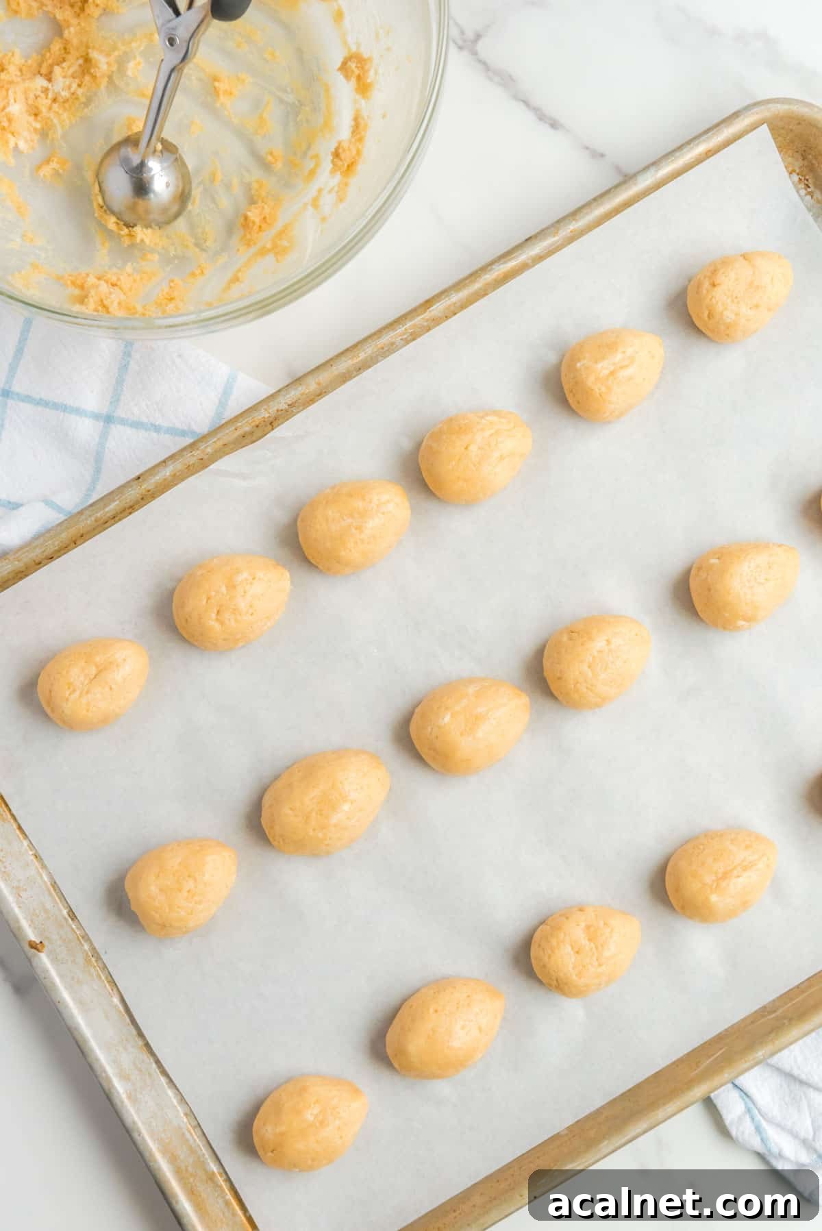 oreo cookie balls shaped into egg shapes, lined up on a baking sheet lined with parchment paper