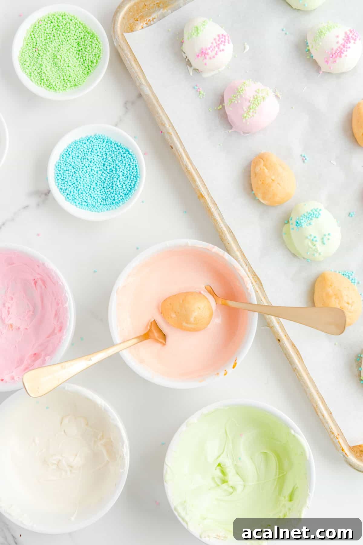 a baking sheet with some dipped and some non-dipped easter egg truffles beside bowls of sprinkles and colored chocolate