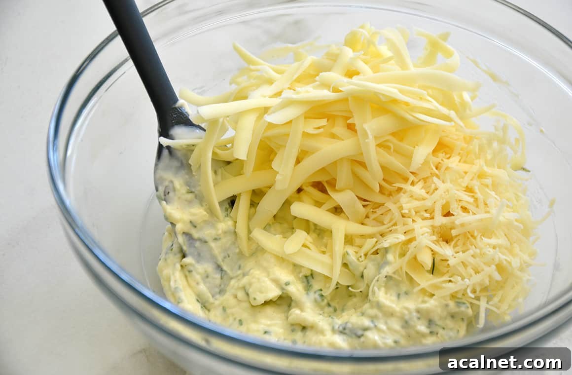 A clear bowl containing garlic butter and mayonnaise mixture topped with shredded mozzarella cheese