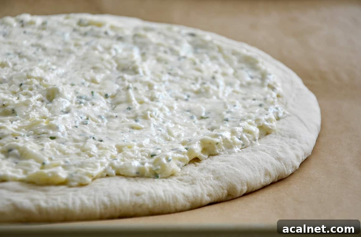 Pizza dough topped with garlic cheese mixture atop parchment paper