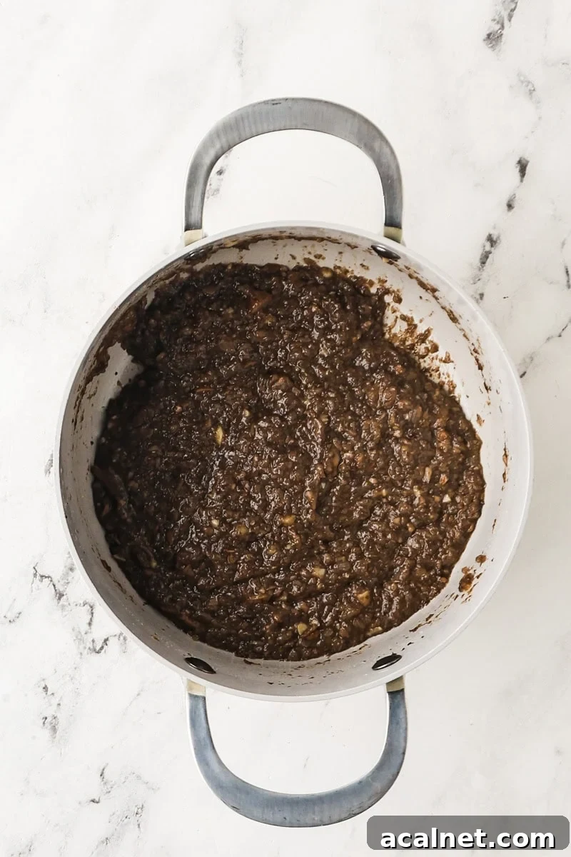 Sherry added in the mushroom mixture for mushroom gravy in a saucepan.