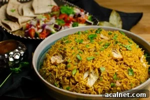Pressure cooker Chicken Biryani served in a green bowl with chopped coriander on top, salad and mango chutney served on the side