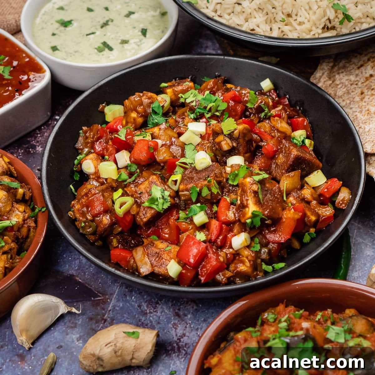A black bowl of chilli paneer curry