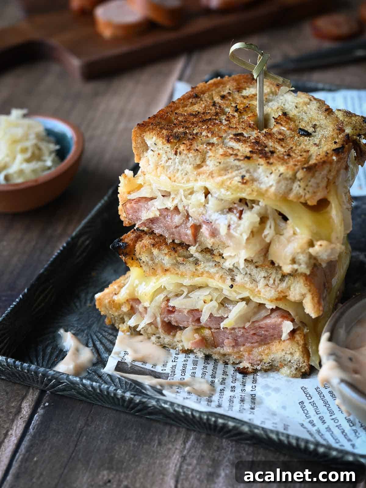 Kielbasa Reuben Sandwich Recipe — Smoky Sausage & Sauerkraut Melt 11 Kielbasa sandwiches stacked on top of each other with condiments on the side.