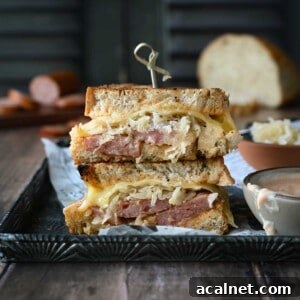 Kielbasa Reuben Sandwich Recipe — Smoky Sausage & Sauerkraut Melt 16 Kielbasa sandwiches stacked on top of each other with condiments on the side.