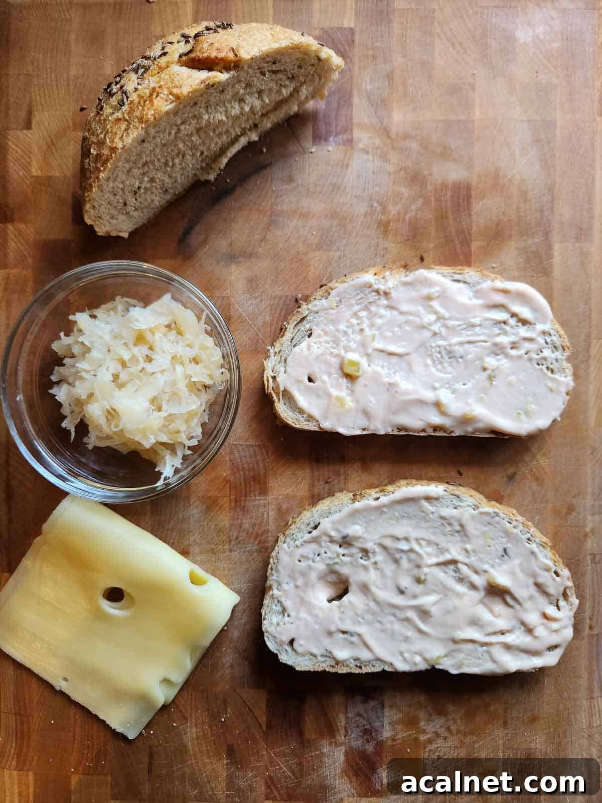 Kielbasa Reuben Sandwich Recipe — Smoky Sausage & Sauerkraut Melt 5 Bread, sauerkraut, dressing, and cheese on a cutting board.