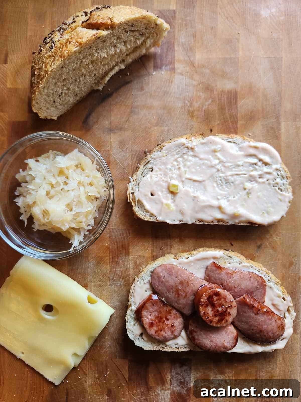 Kielbasa Reuben Sandwich Recipe — Smoky Sausage & Sauerkraut Melt 6 Bread, sauerkraut, meat, and cheese on a cutting board.