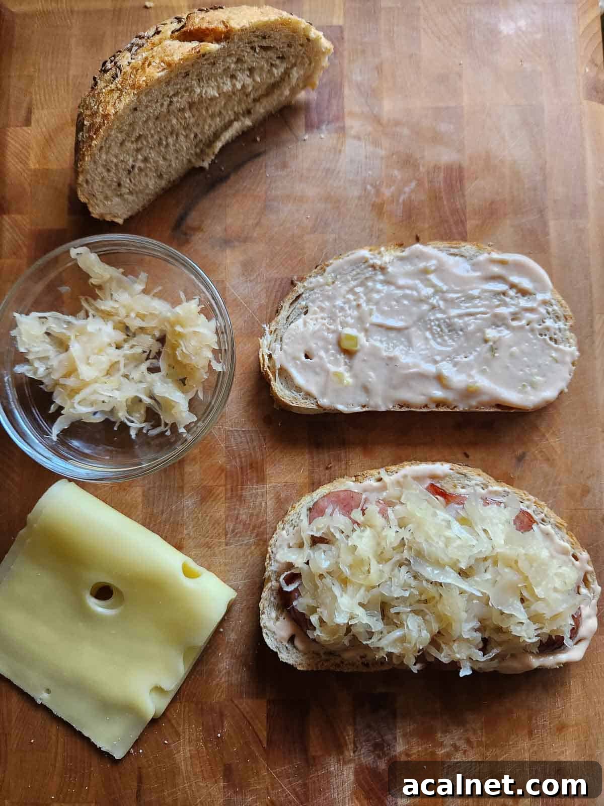 Kielbasa Reuben Sandwich Recipe — Smoky Sausage & Sauerkraut Melt 7 Bread, sauerkraut and cheese on a cutting board.