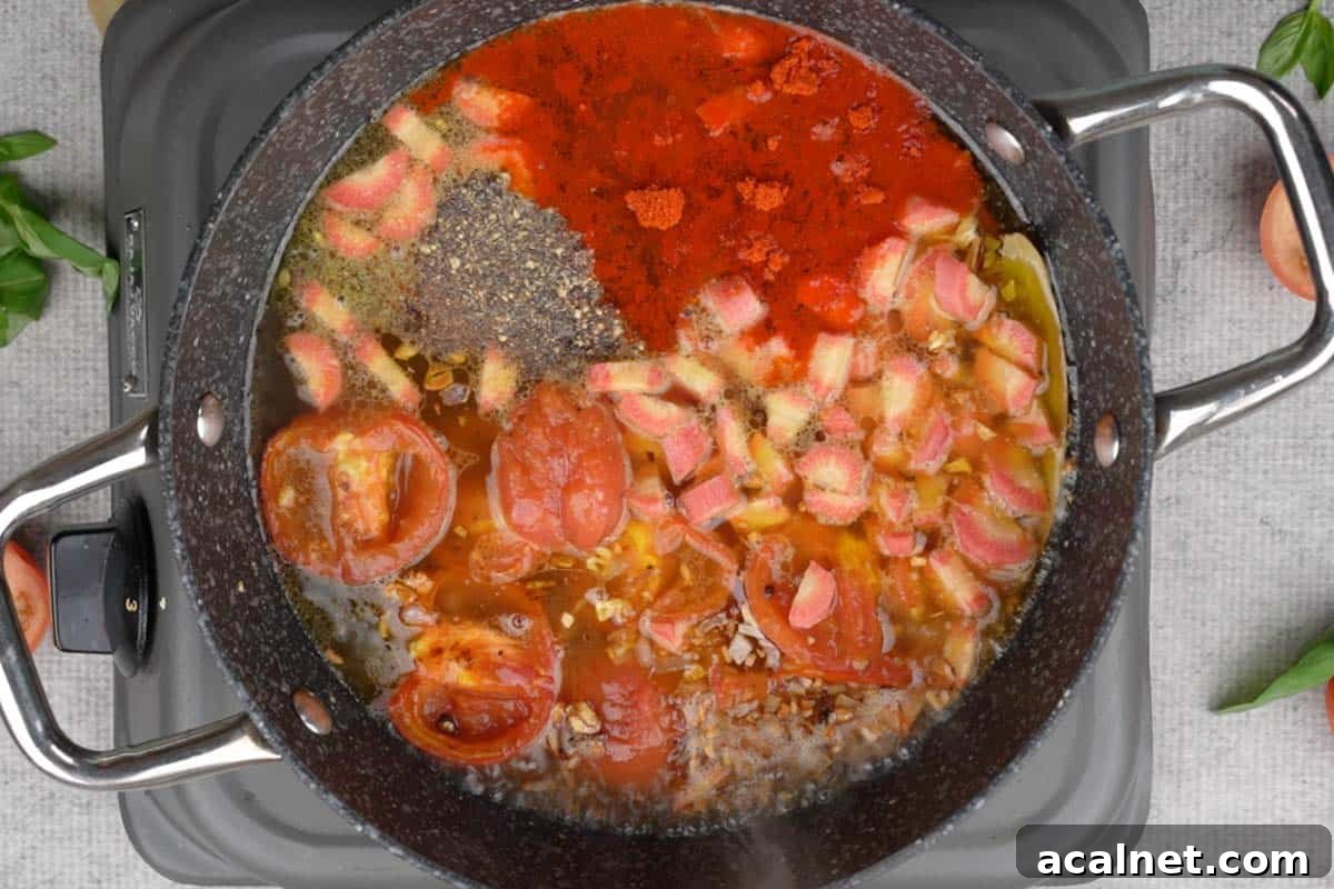 Roasted tomatoes, carrot, vegetable stock, salt, black pepper and cayenne pepper added to the pan.