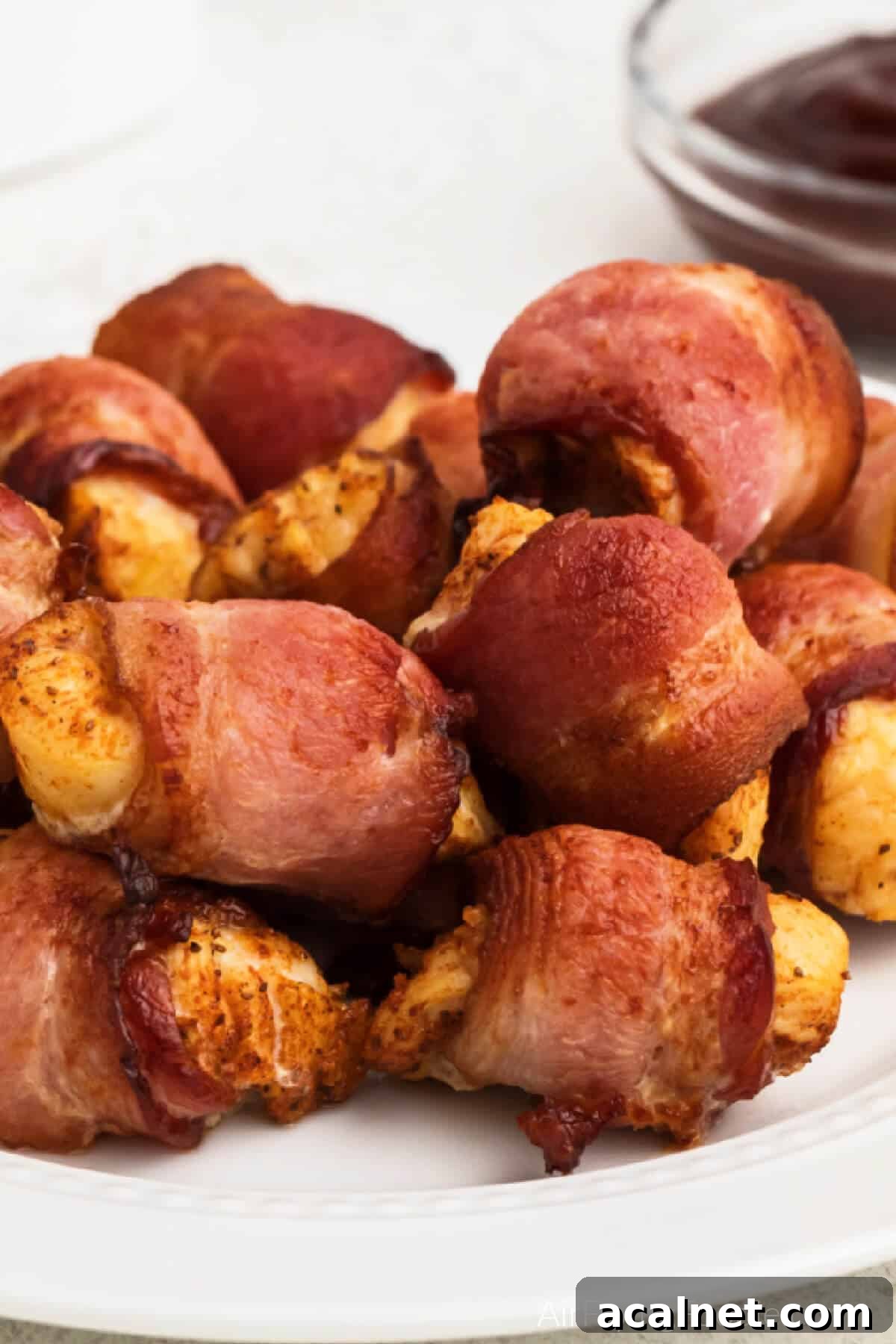 Bacon wrapped chicken bites made in the air fryer and served on a white plate. 