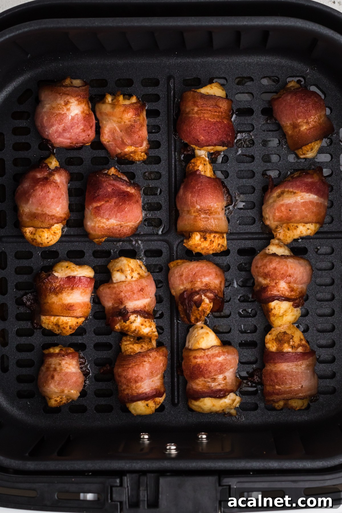 Fully cooked bacon wrapped chicken bites in the basket of the air fryer. 