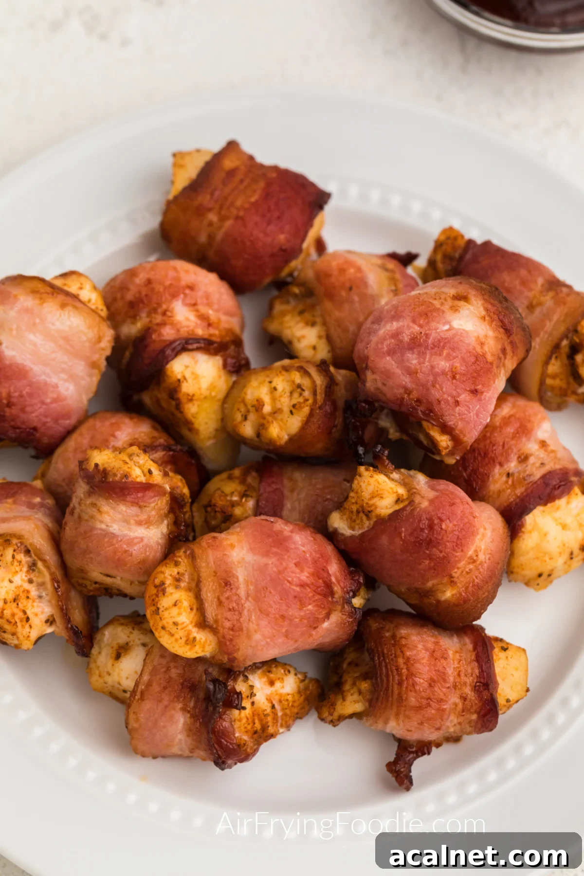 Bacon wrapped chicken bites on a white plate ready to serve. 