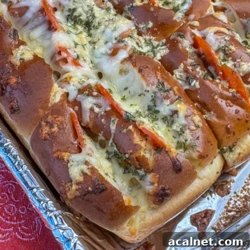 Close up top of a Hawaiian roll with slits cut in the top and stuffed with pepperoni and Italian cheese and baked until golden brown.