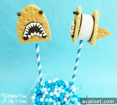 S'mores pops decorated to look like sharks in front of a teal-colored backdrop