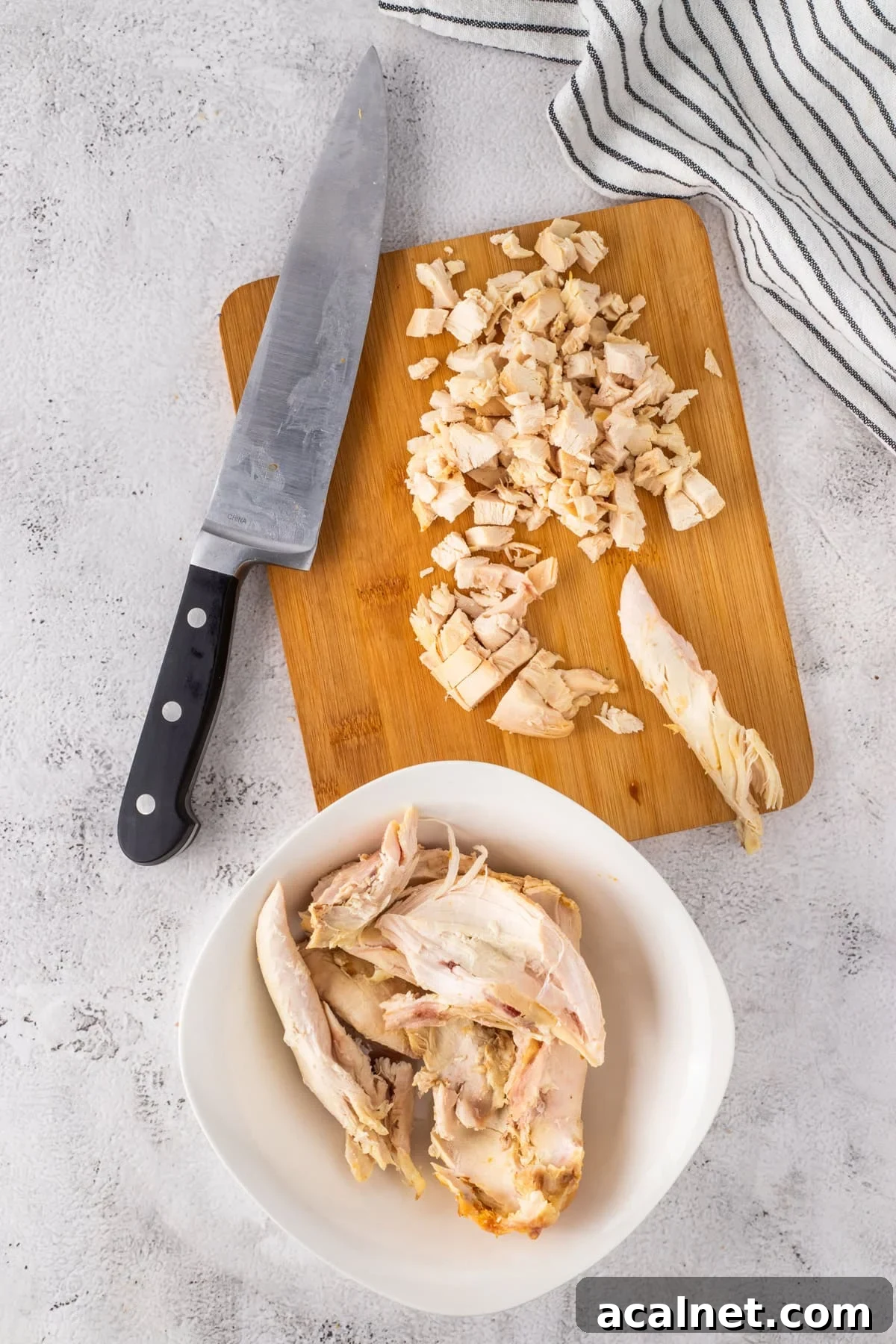 Some shredded and chopped chicken on a cutting board.