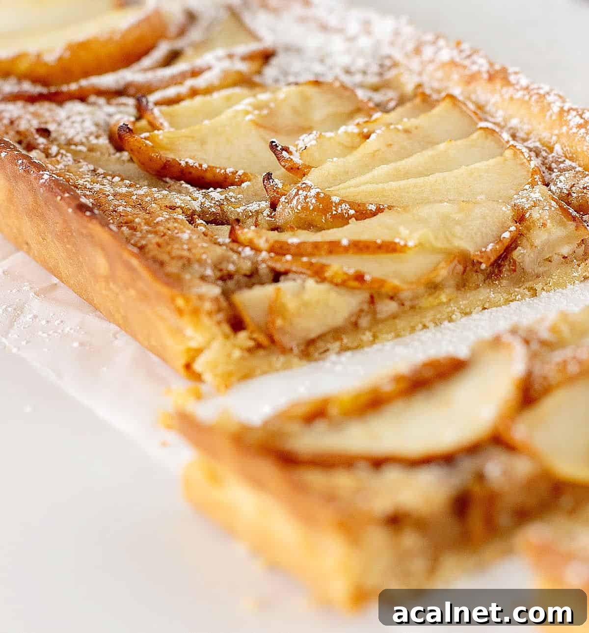 Partial view of pear frangipane tart on white surface