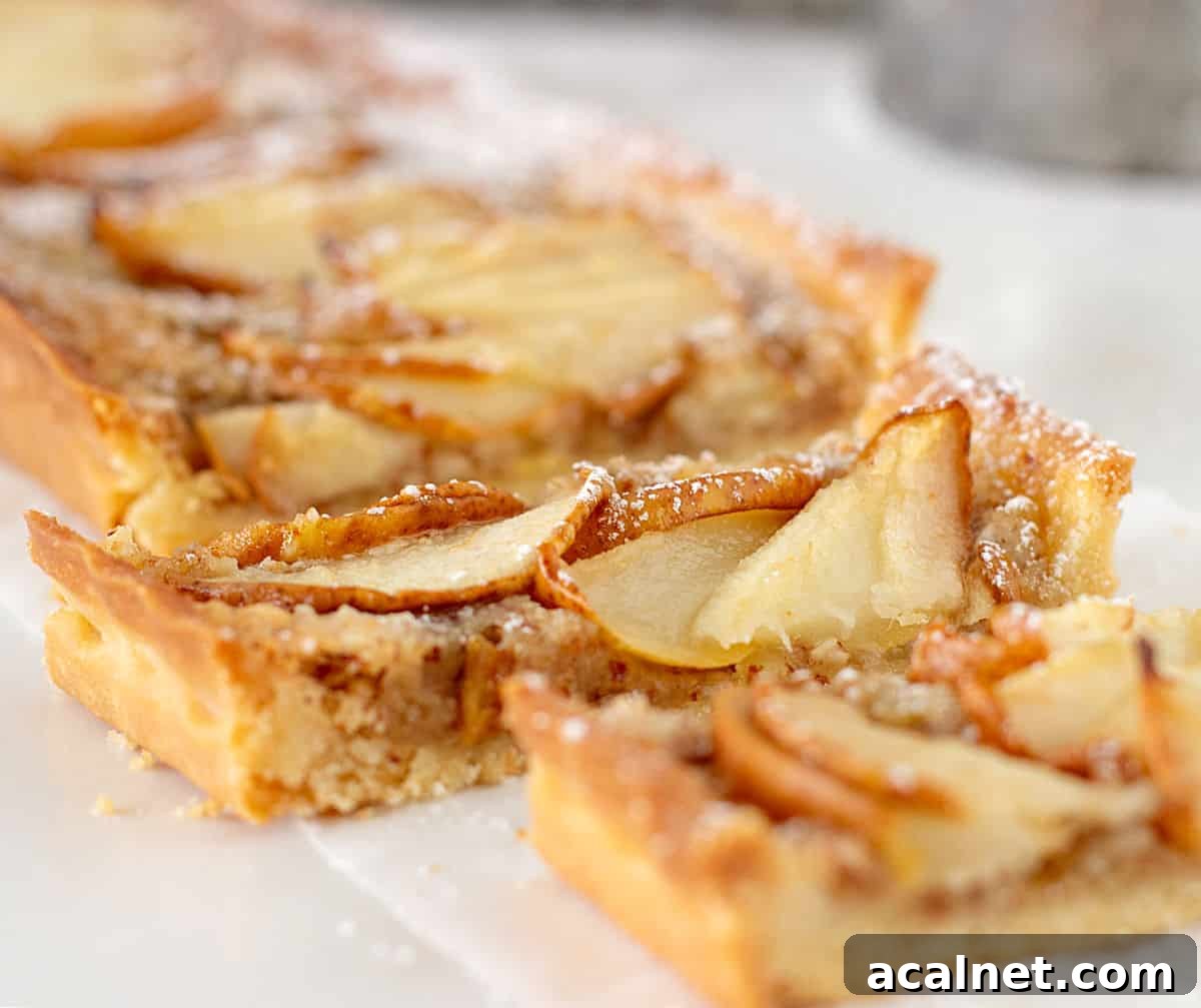 Close up of rectangular pear tart on white parchment paper.