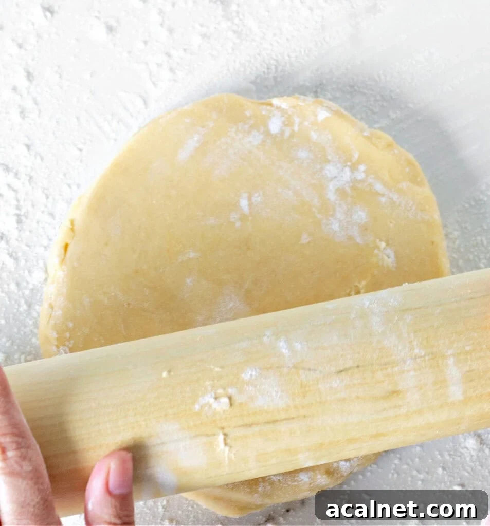 Rolling pie dough on a white surface. Rolling pin.