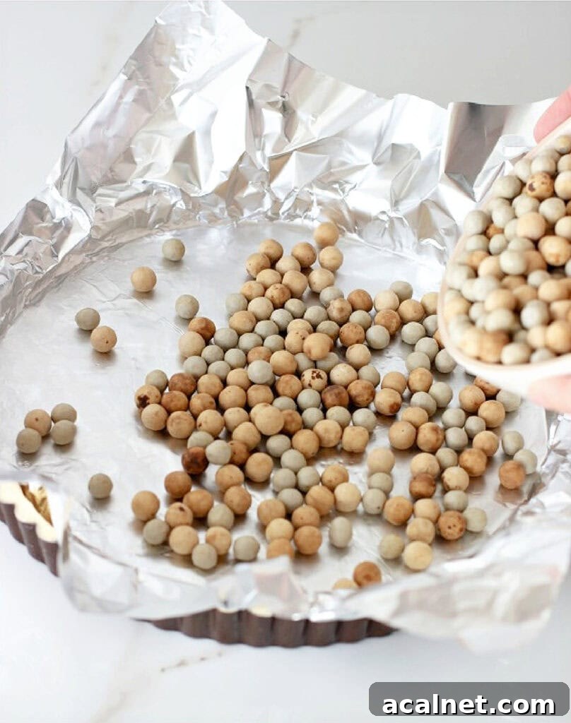 Aluminum foil with pie weights over tart crust in pan.