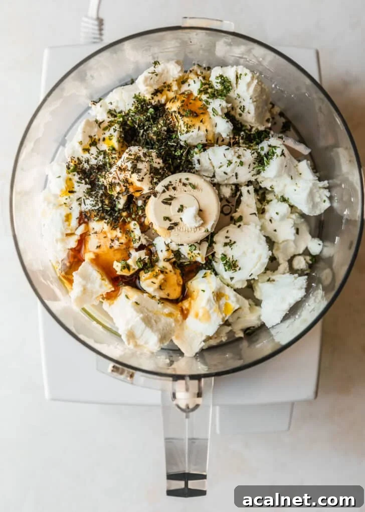 A food processor with cheese, honey, and herbs.