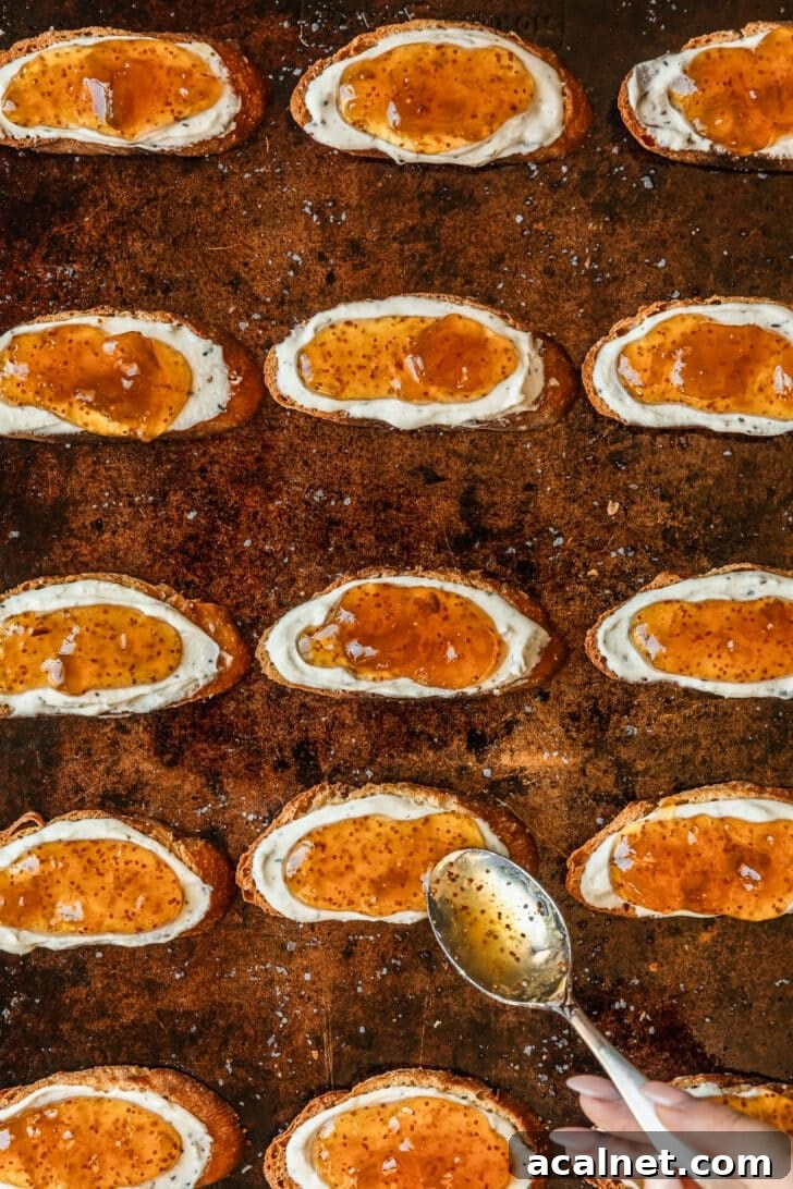 A hand spreading fig jam on toasts.