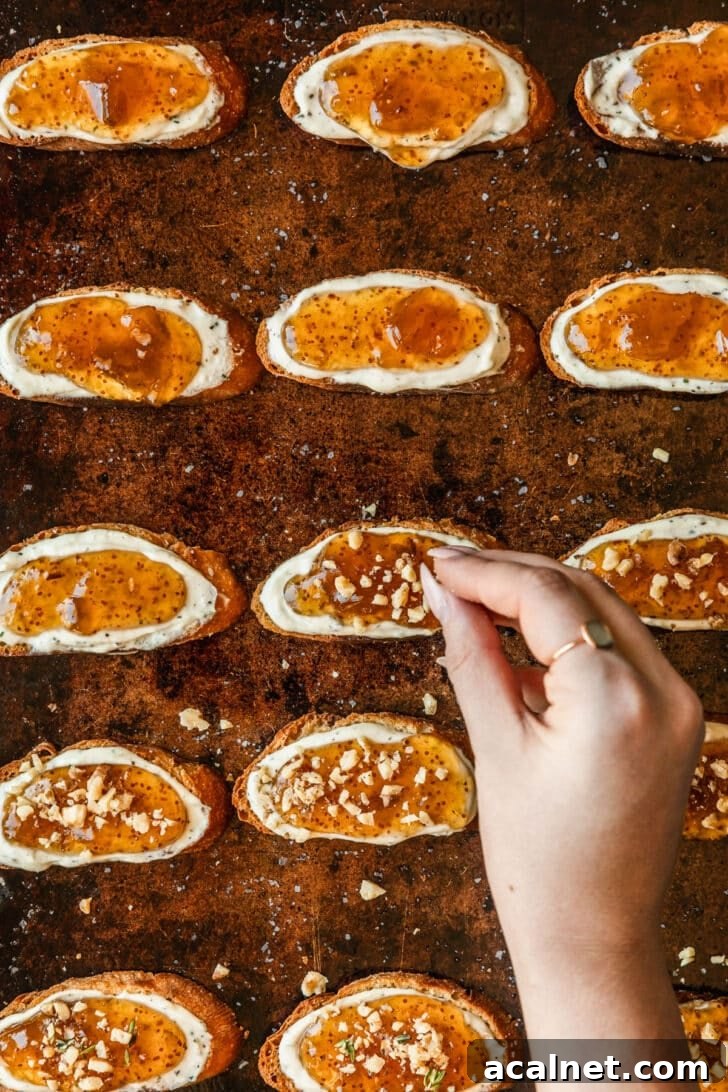 A hand sprinkling walnuts on crostini.