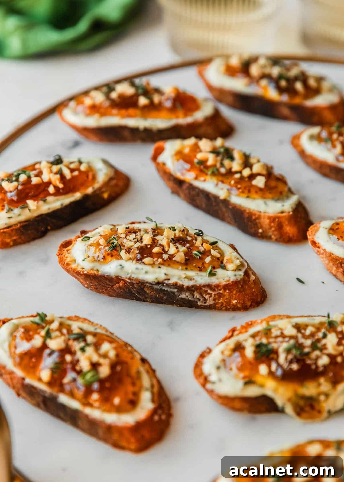 Fig goat cheese crostini on a marble board next to white wine and a green linen.